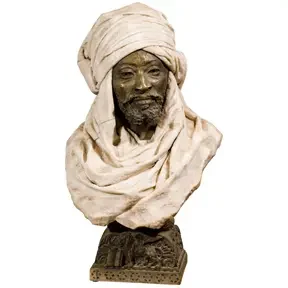 Sculpted bust of a bearded man wearing a wrapped turban, carved in light stone on a decorative base.